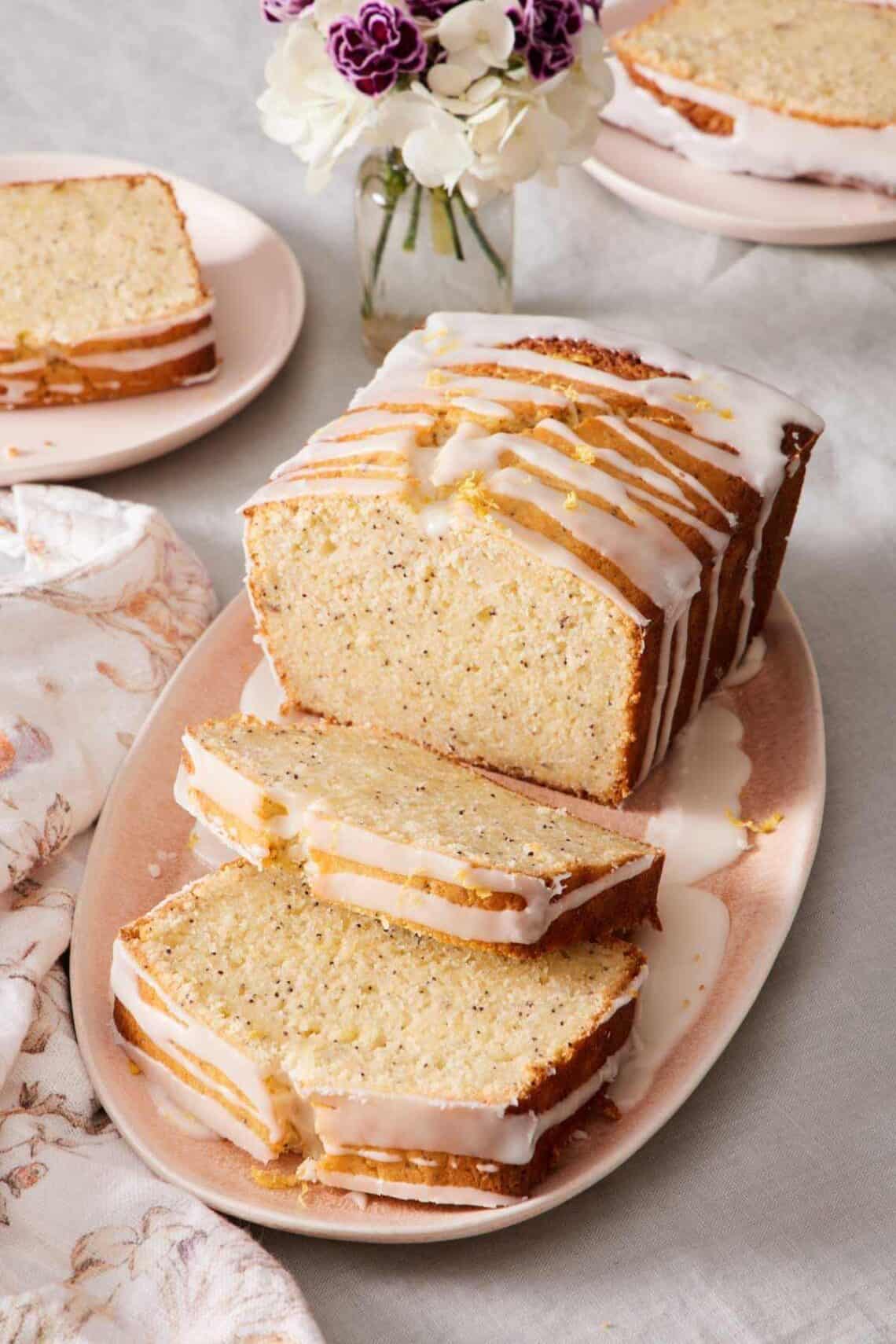 Lemon poppy seed loaf on a platter with a few slices cut out.