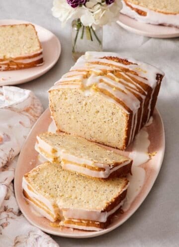 Lemon poppy seed loaf on a platter with a few slices cut out.