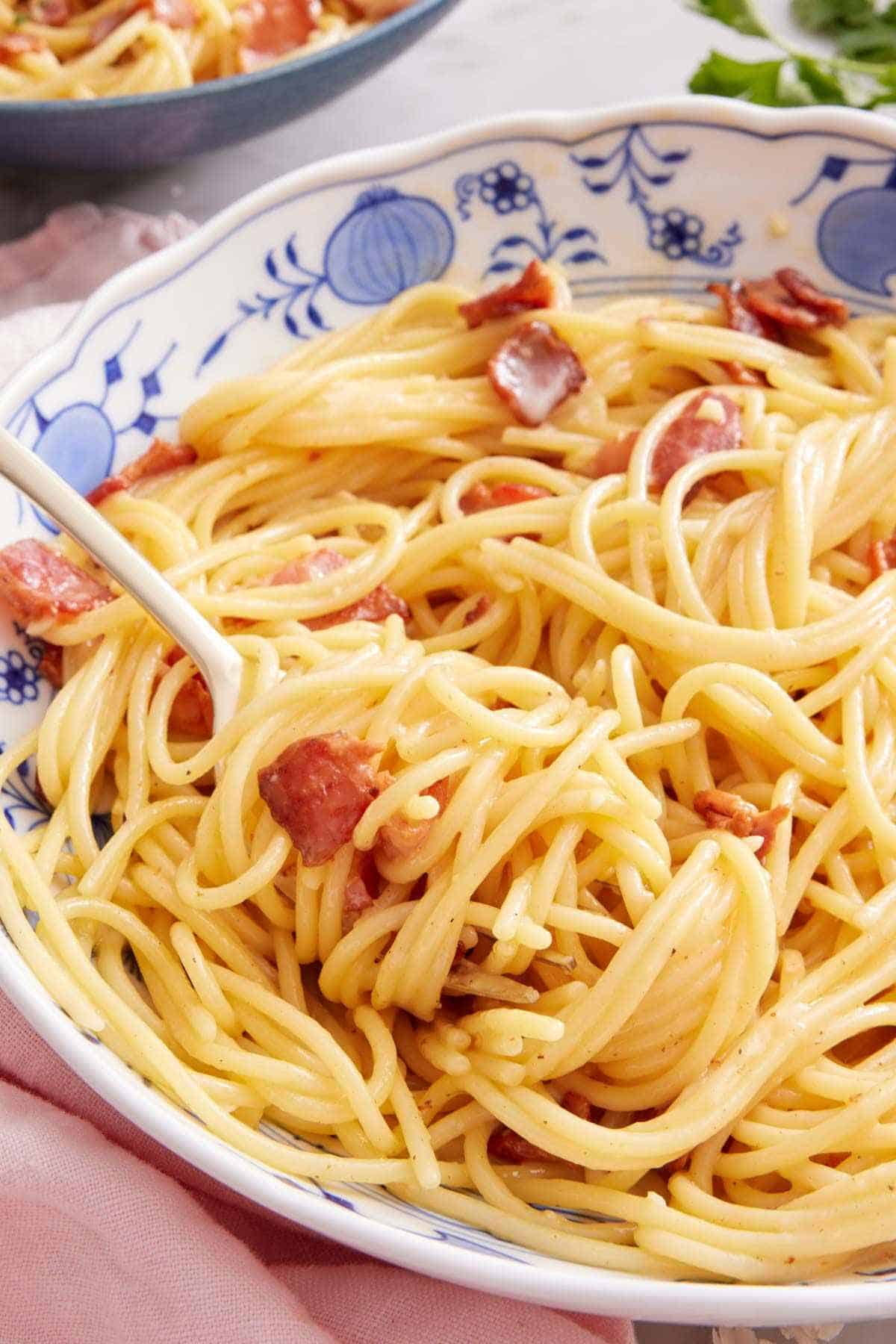 Close-up of pasta carbonara in a blue and white bowl.