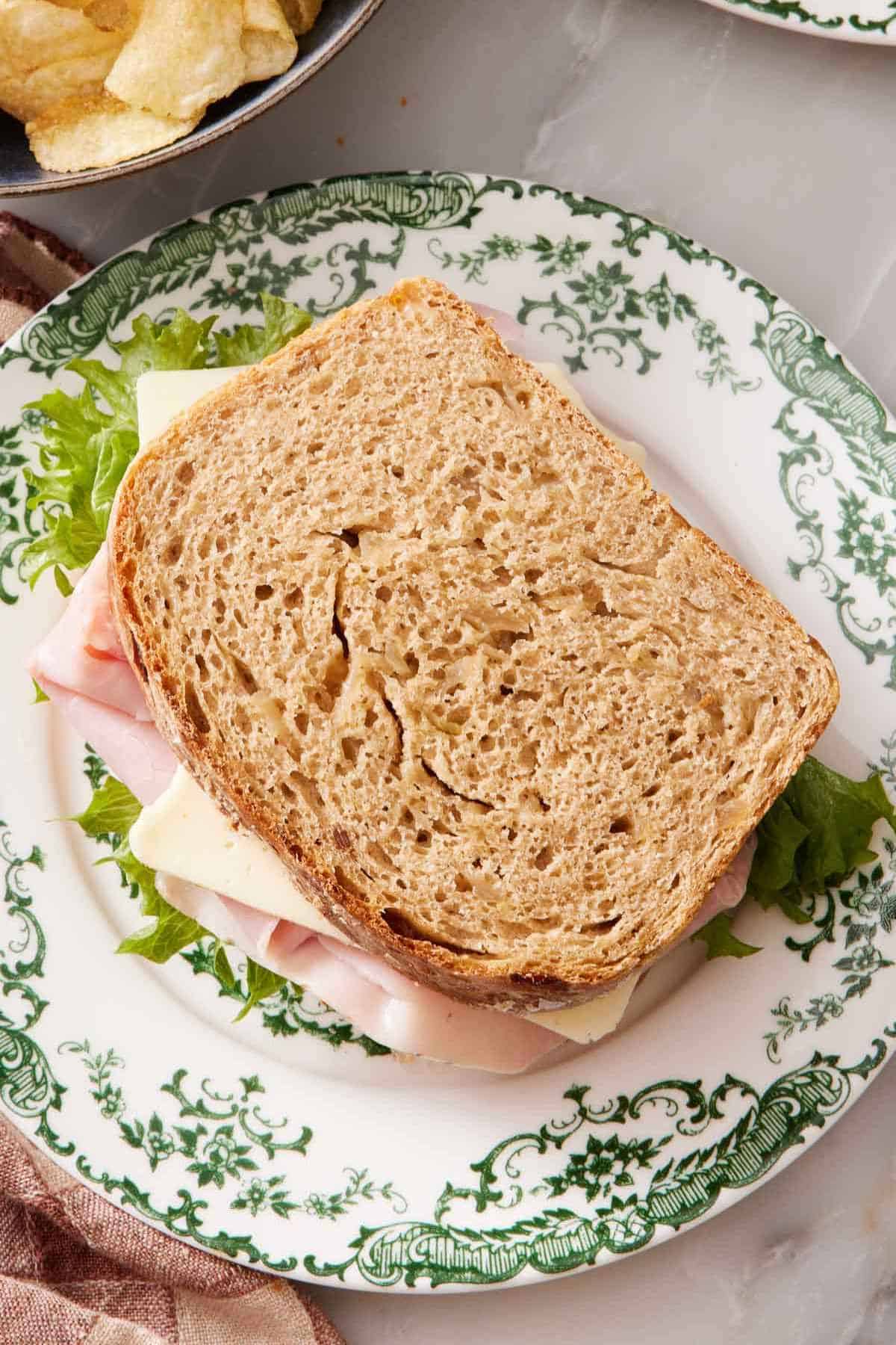 Overhead shot of a sandwich made with homemade bread on a green and white plate.