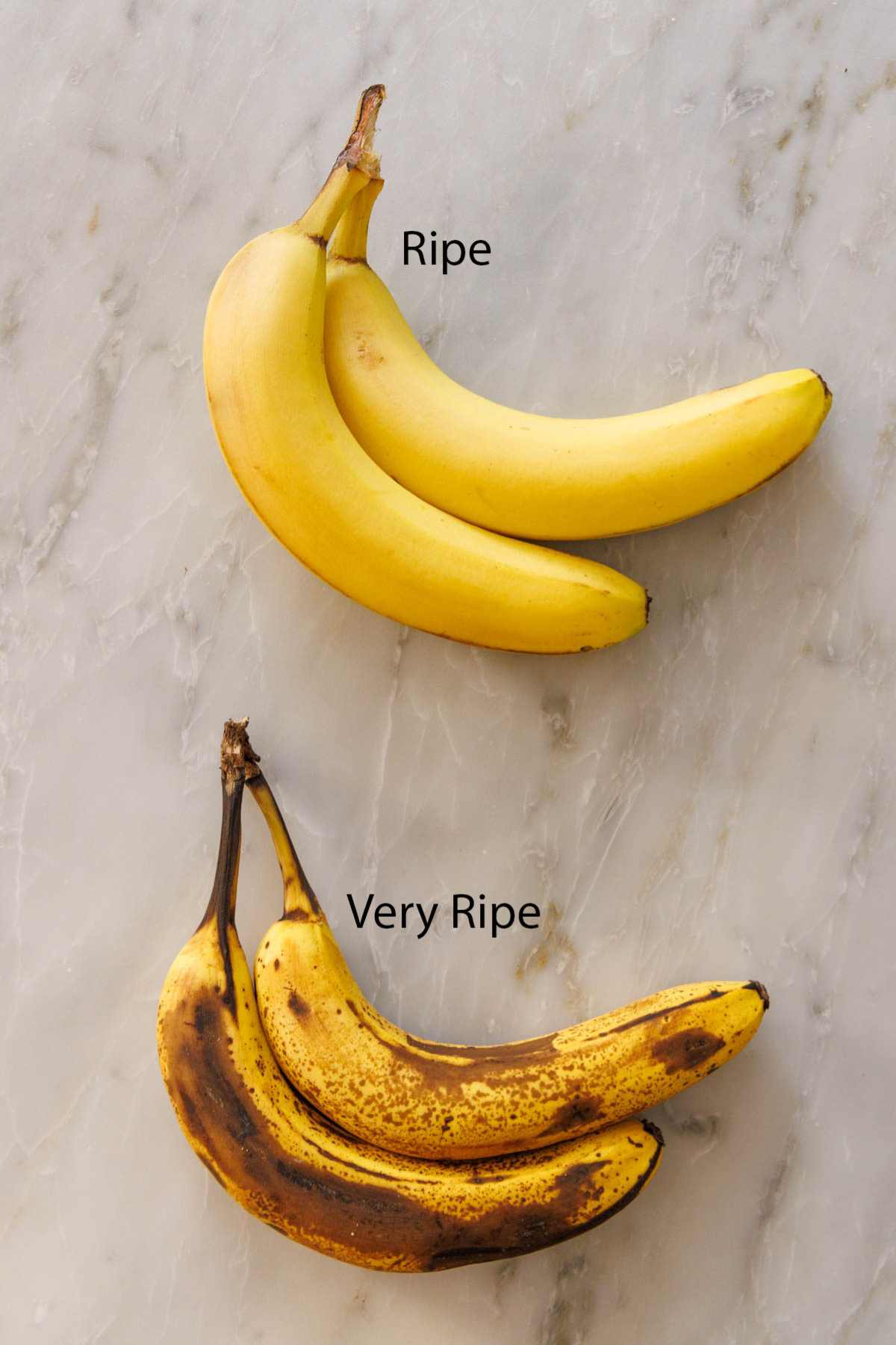 Ripe versus very ripe bananas on a marble counter.