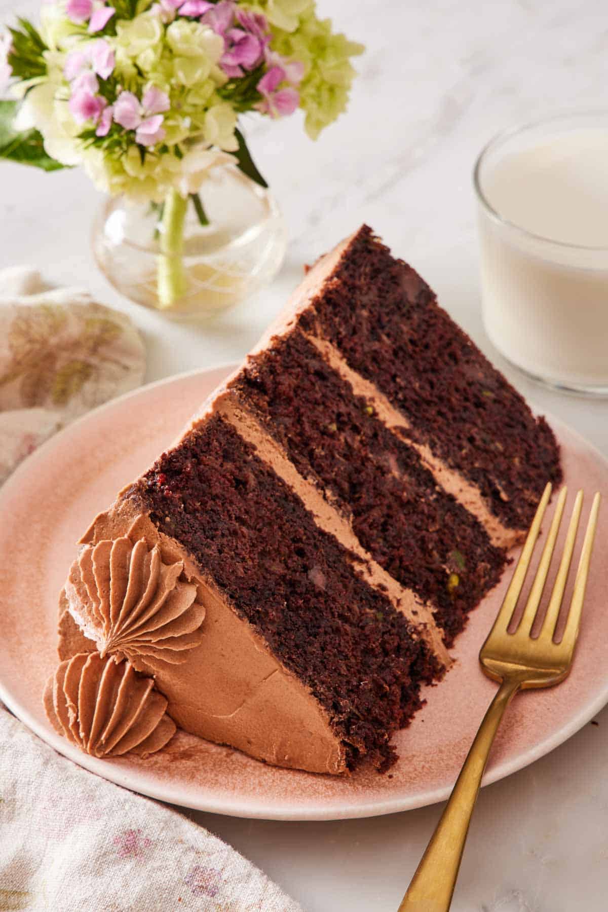 A slice of chocolate zucchini cake laying on its side on a small plate with a fork.