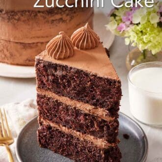 Pinterest graphic showing a slice of chocolate zucchini cake on a small plate with a glass of milk on the side, and the rest of the cake in the background.