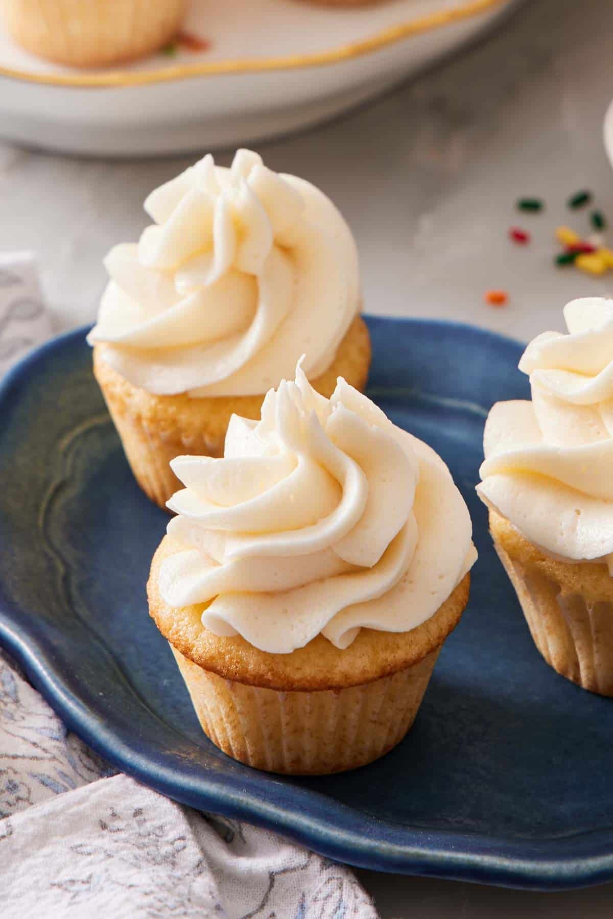 Three frosted cupcakes on a blue platter.