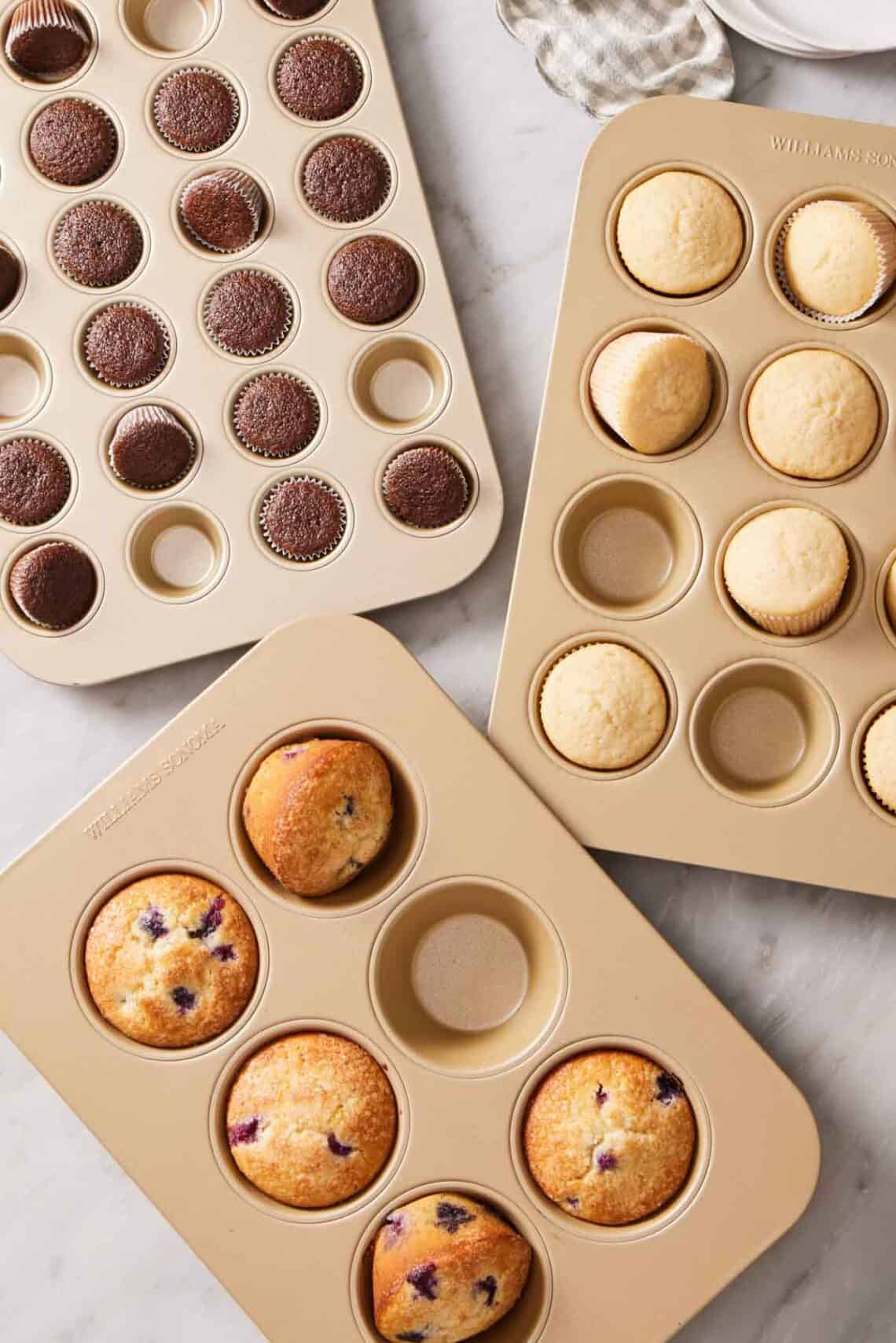 Three different cupcake pans with baked cupcakes filling some of the cavities.