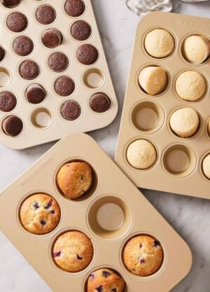 Three different cupcake pans with baked cupcakes filling some of the cavities.