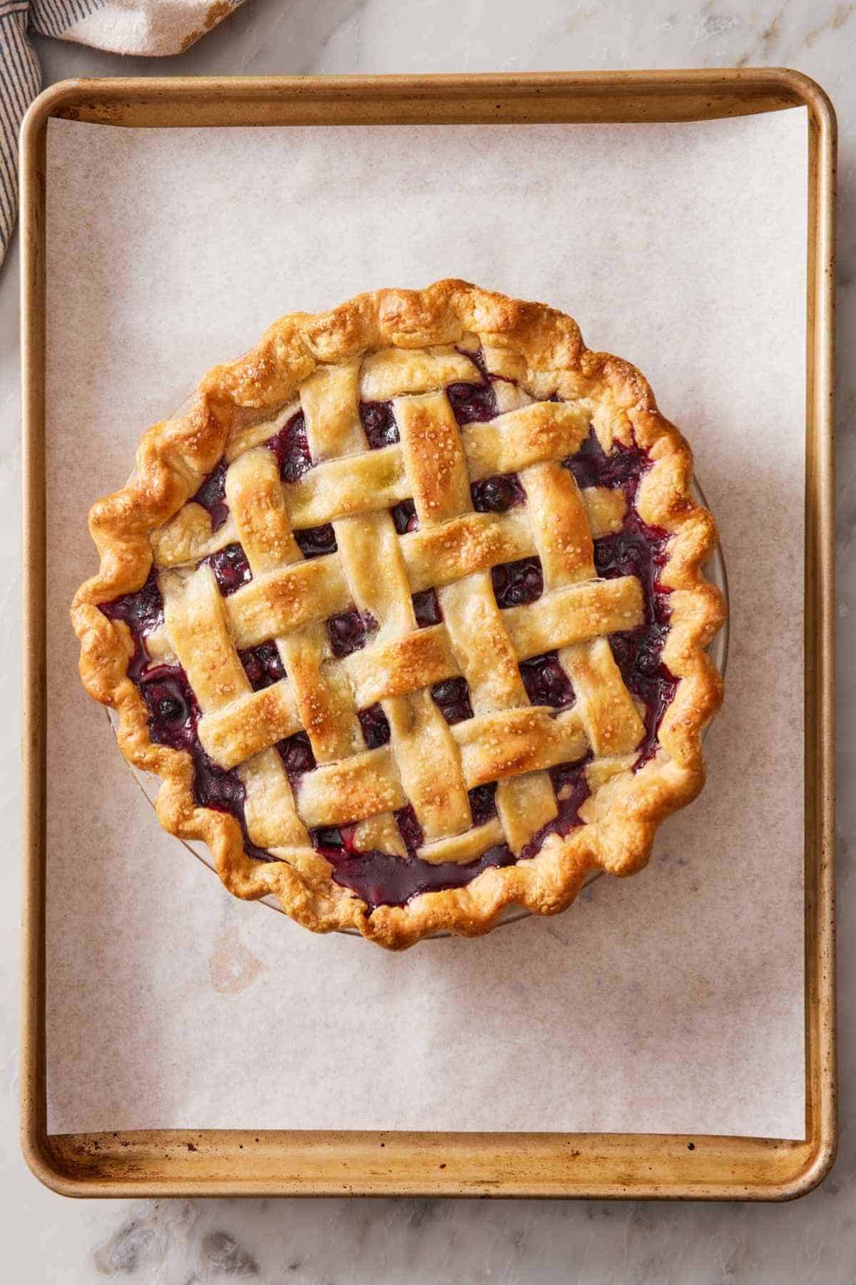 Overhead view of a baked lattice top pie on a lined baking sheet.