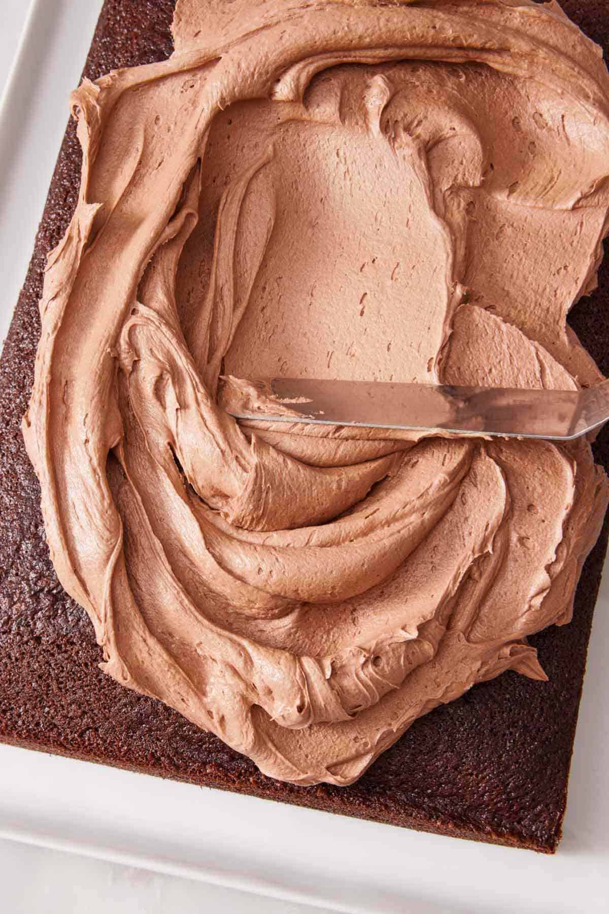 Overhead shot of chocolate buttercream spread on a chocolate sheet cake.