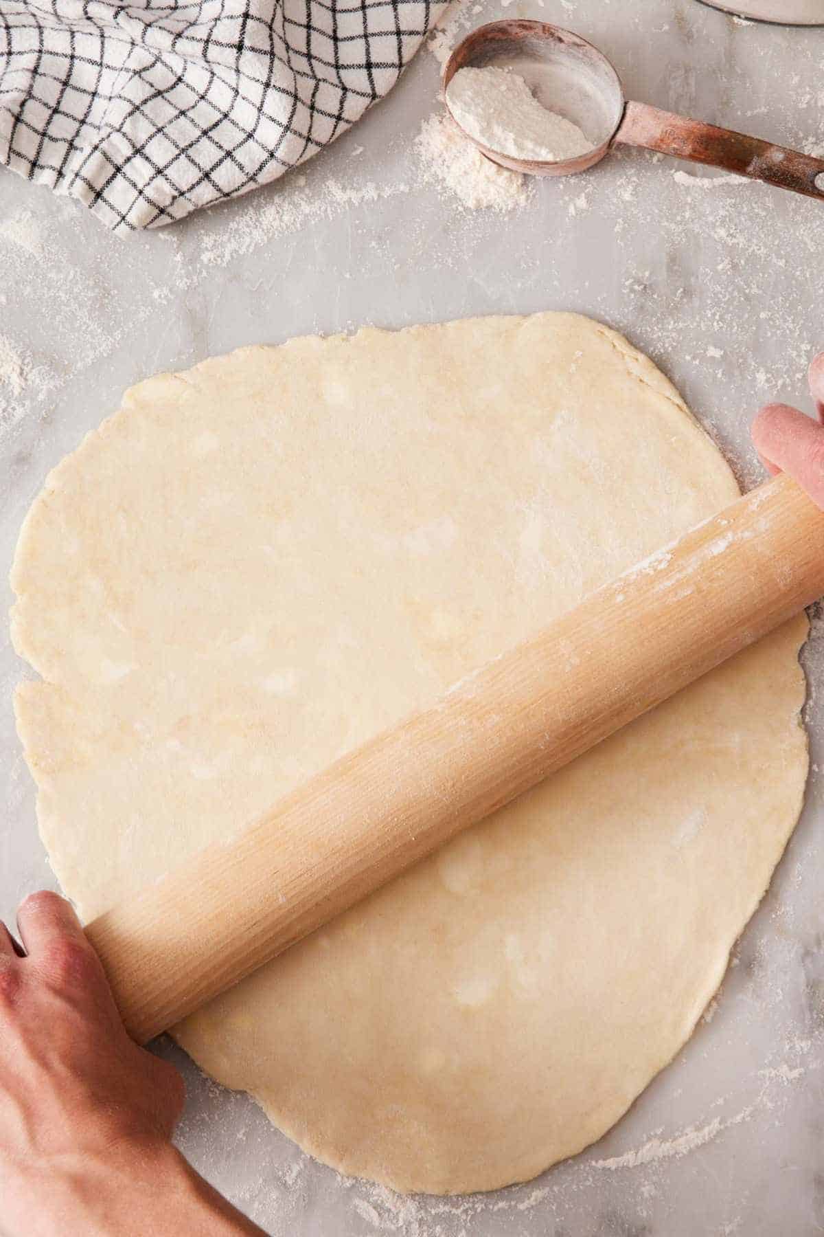 Pie dough rolled out on a marble countertop.