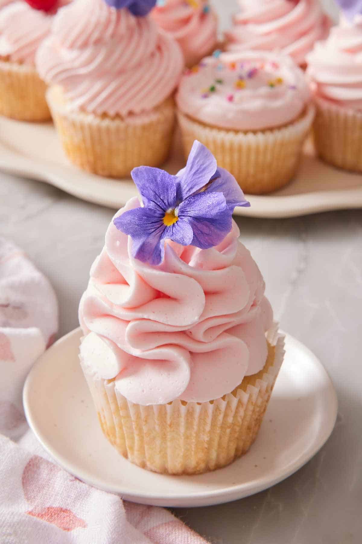 Close-up of a frosted cupcake, with more cupcakes in the background.