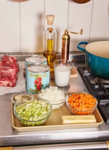 Mise en place with chopped vegetables, canned tomatoes, oil, and beef.