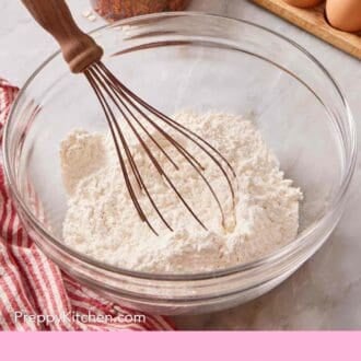 Pinterest graphic showing flour in a glass bowl with a whisk with other baking ingredients behind it.