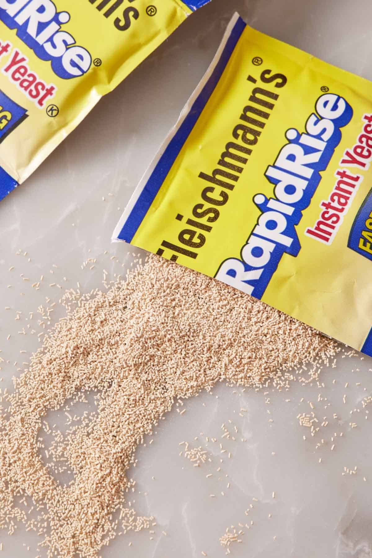 Close-up of a sachet of instant yeast opened and sprinkled on a counter.