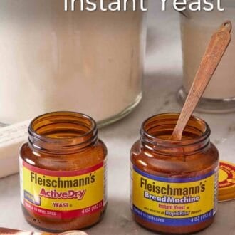 Pinterest graphic showing two jars of different yeast side by side with a spoon in one jar and a spoon next to the other. Flour and a measuring cup of milk behind.