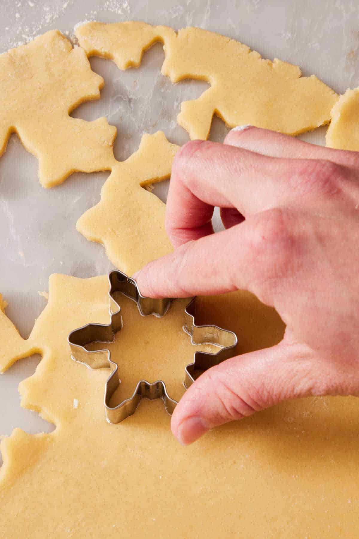 Shapes cut out of cookie dough using a cookie cutter.