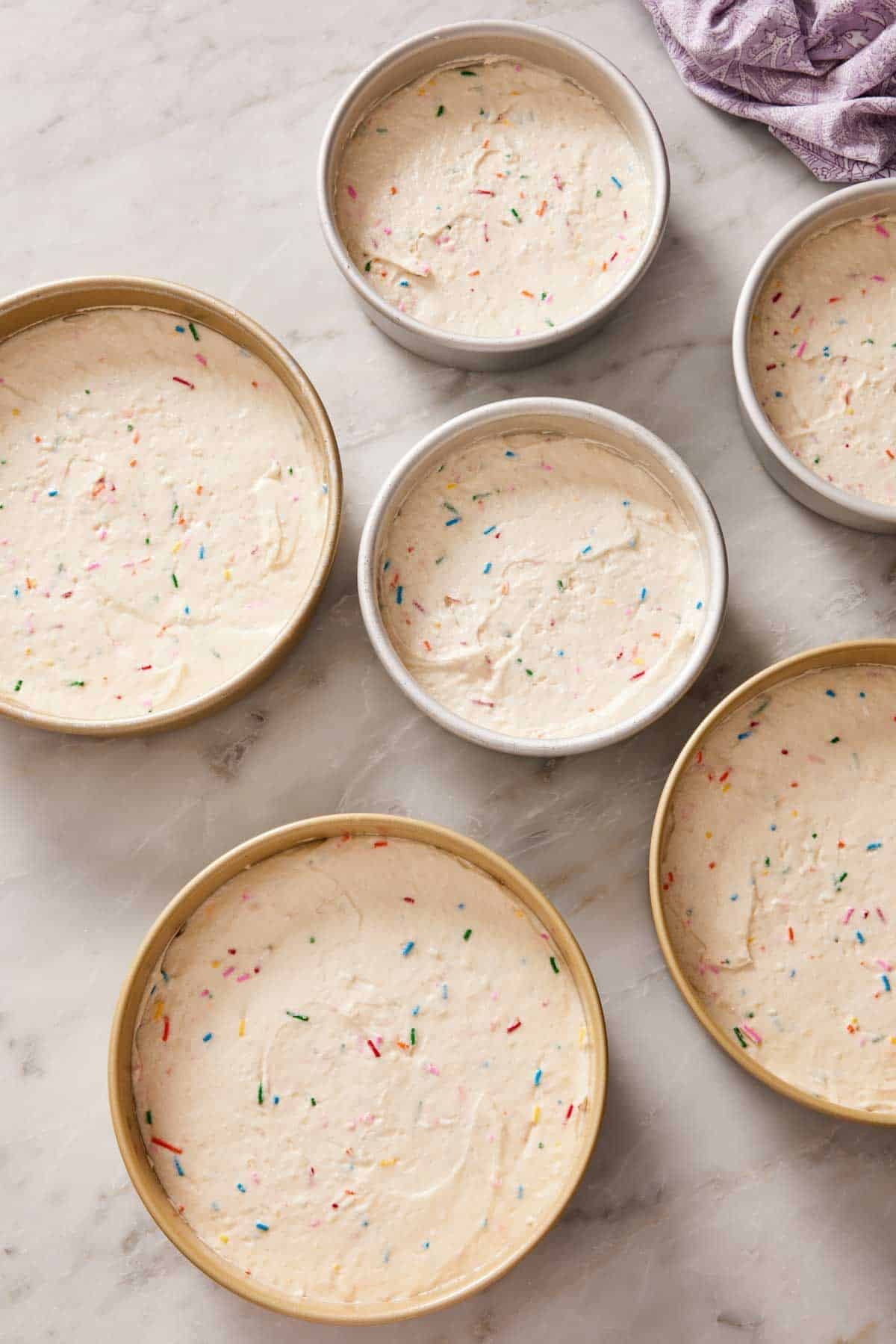 Overhead shot of funfetti cake batter scaled for different pan sizes.