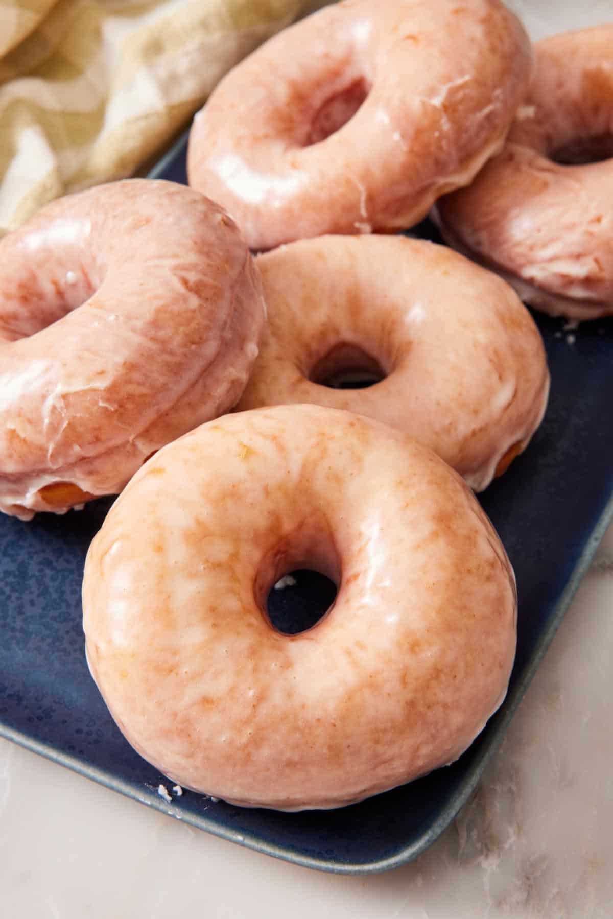 Glazed donuts on a blue platter.
