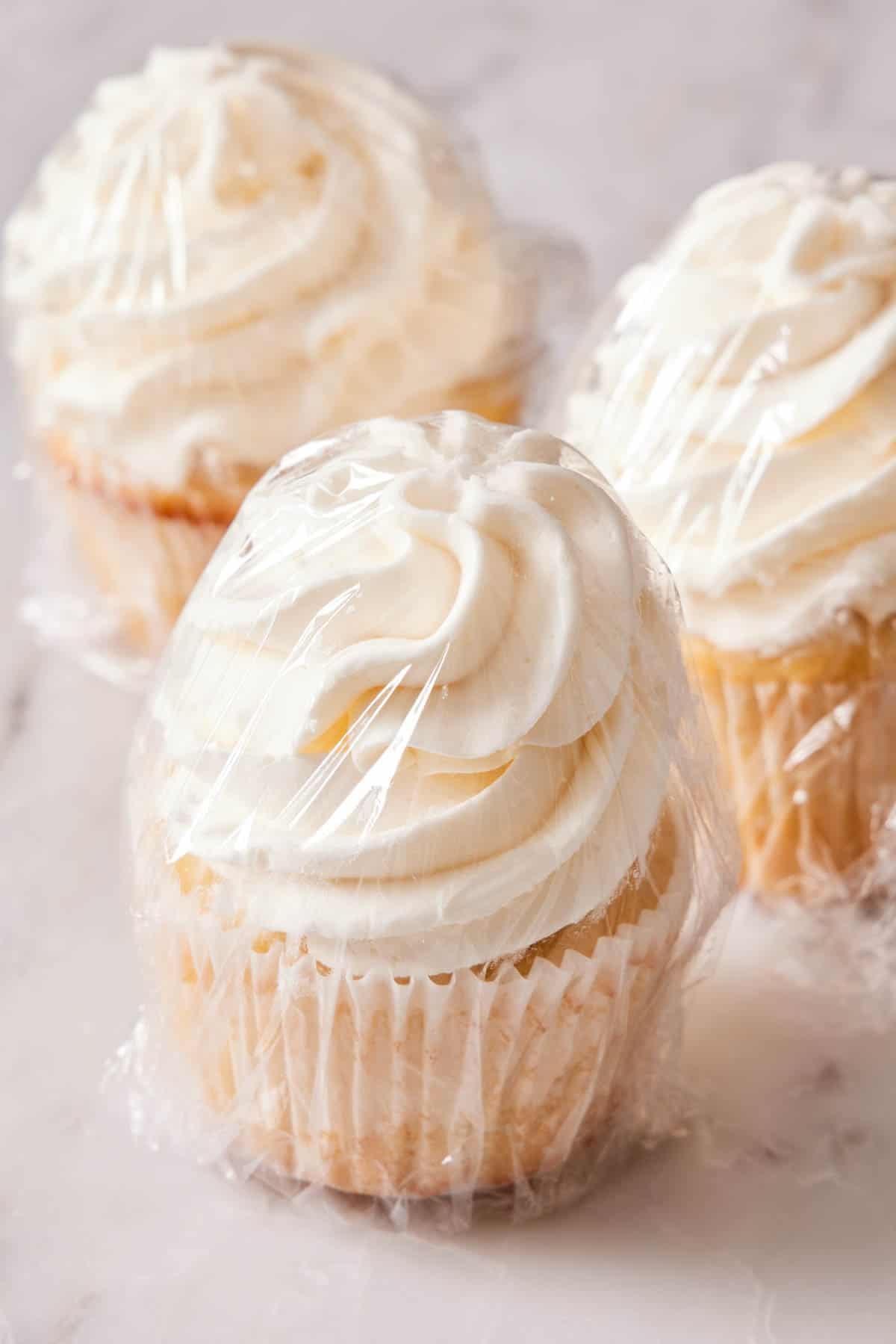 Frosted cupcakes wrapped in plastic wrap prepped for freezing.