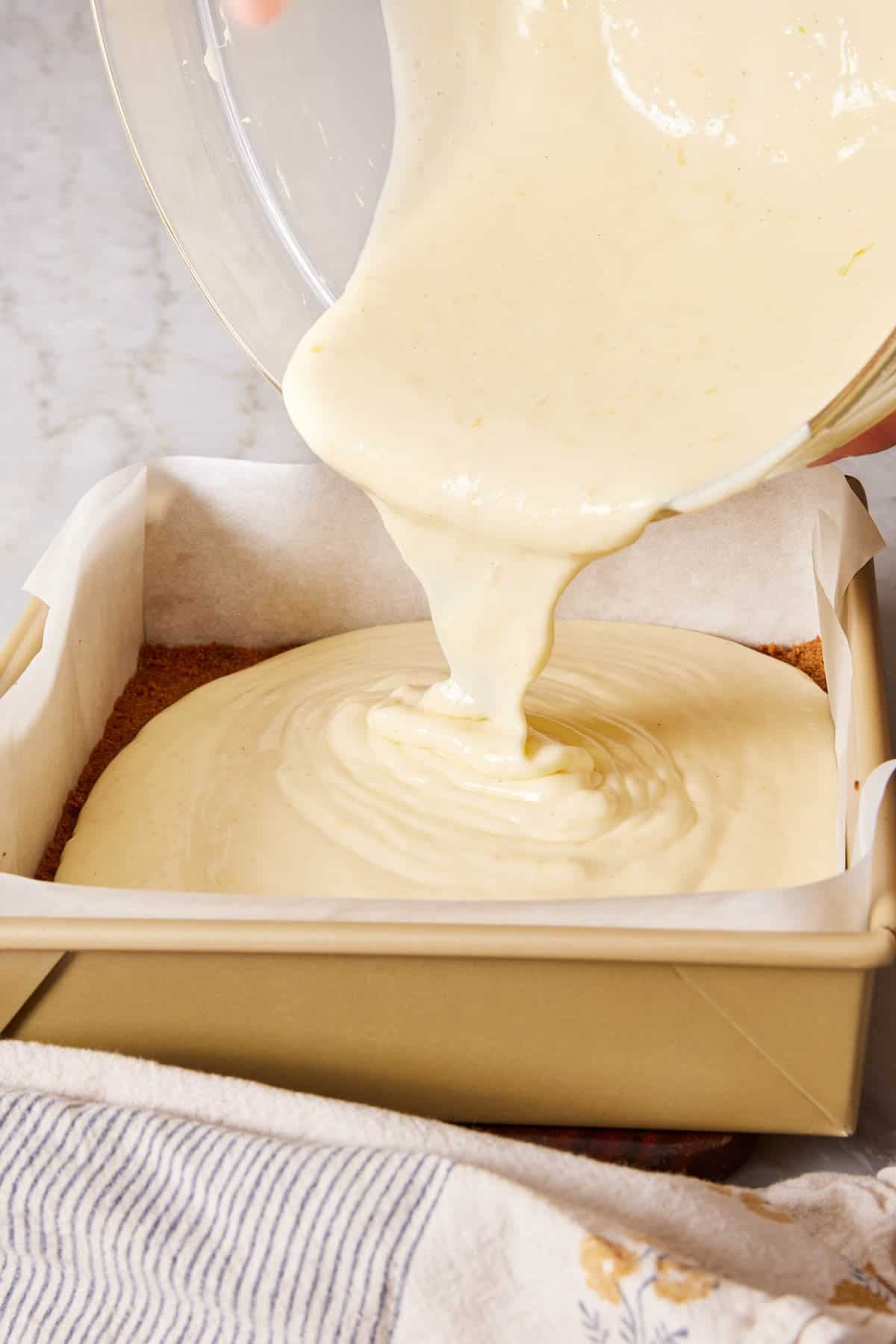 Batter poured into a lined square cake pan.