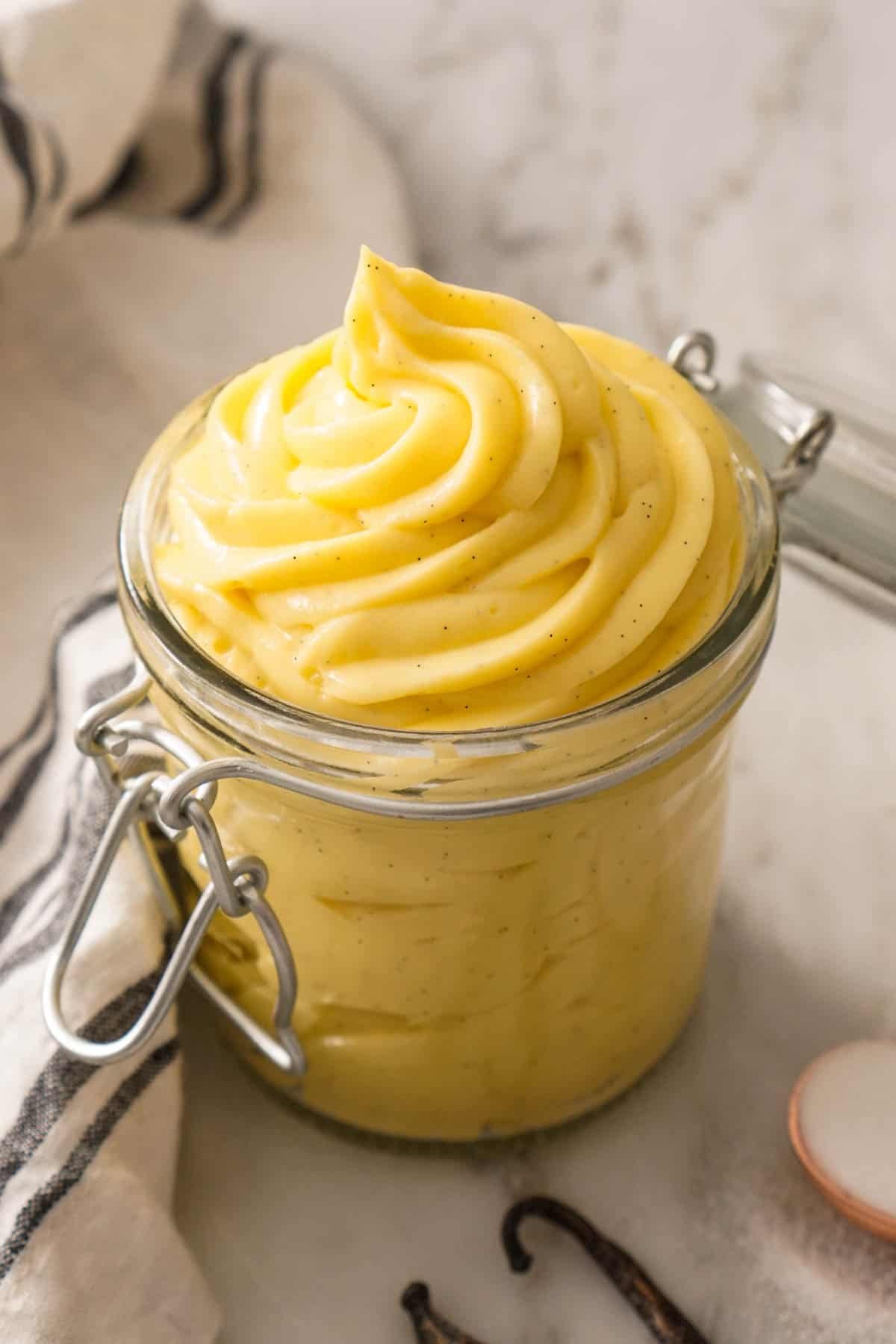A jar full of pastry cream on a marble counter.
