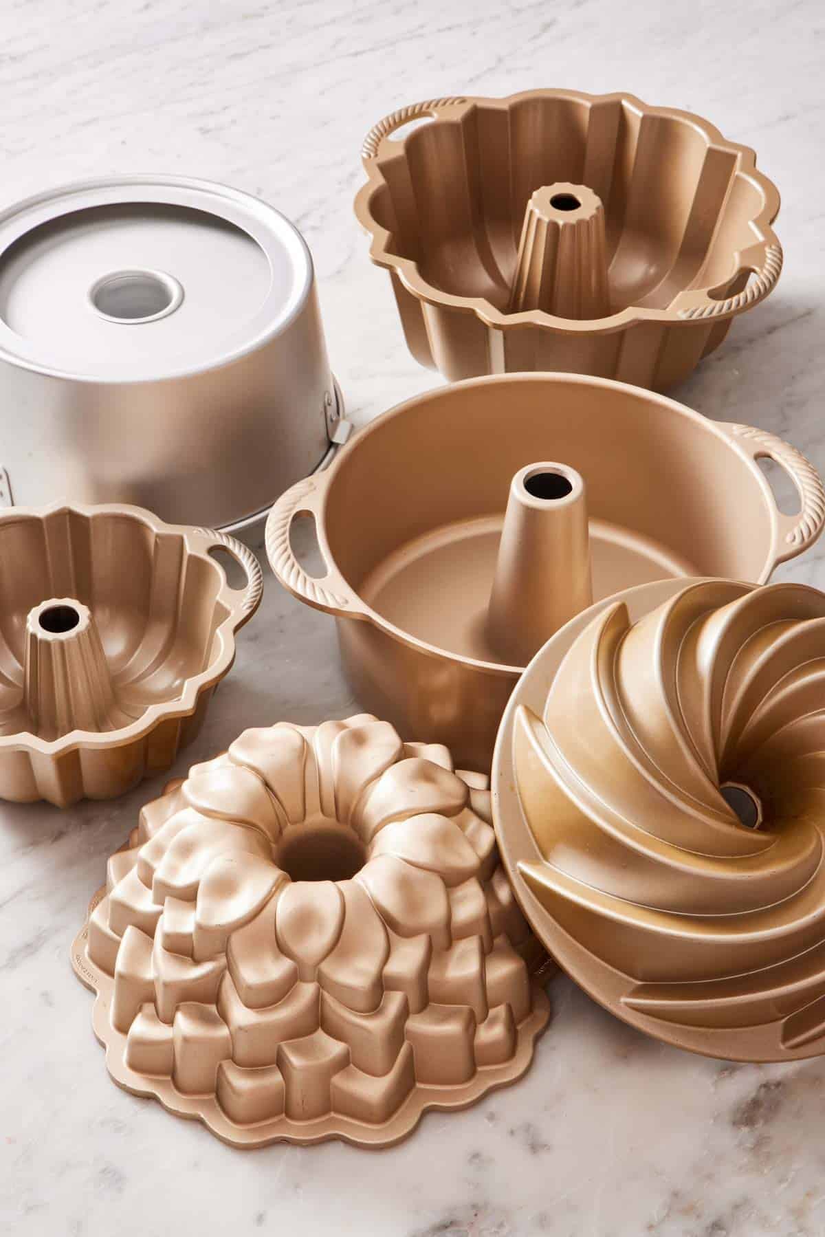 Various Bundt pans on a marble countertop.