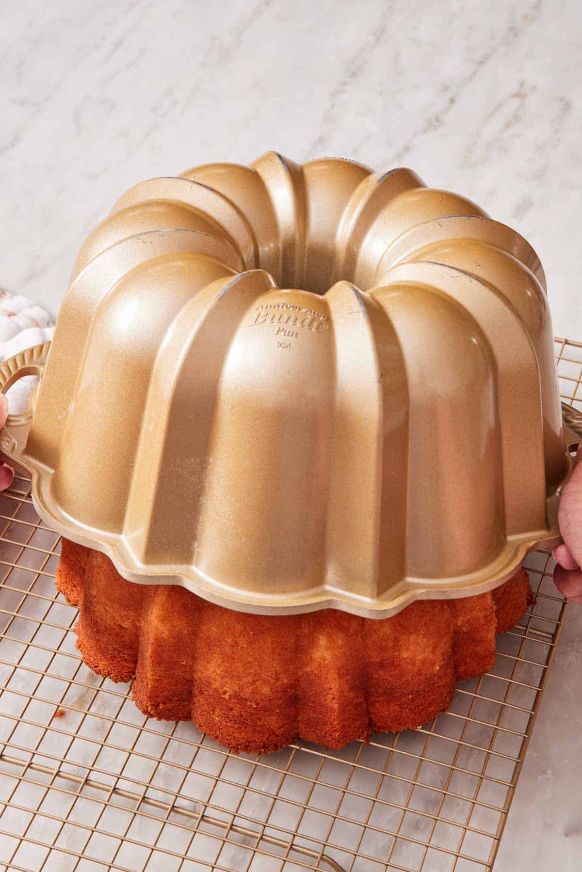 A Bundt cake inverted and being released from a Bundt pan onto a wire rack.