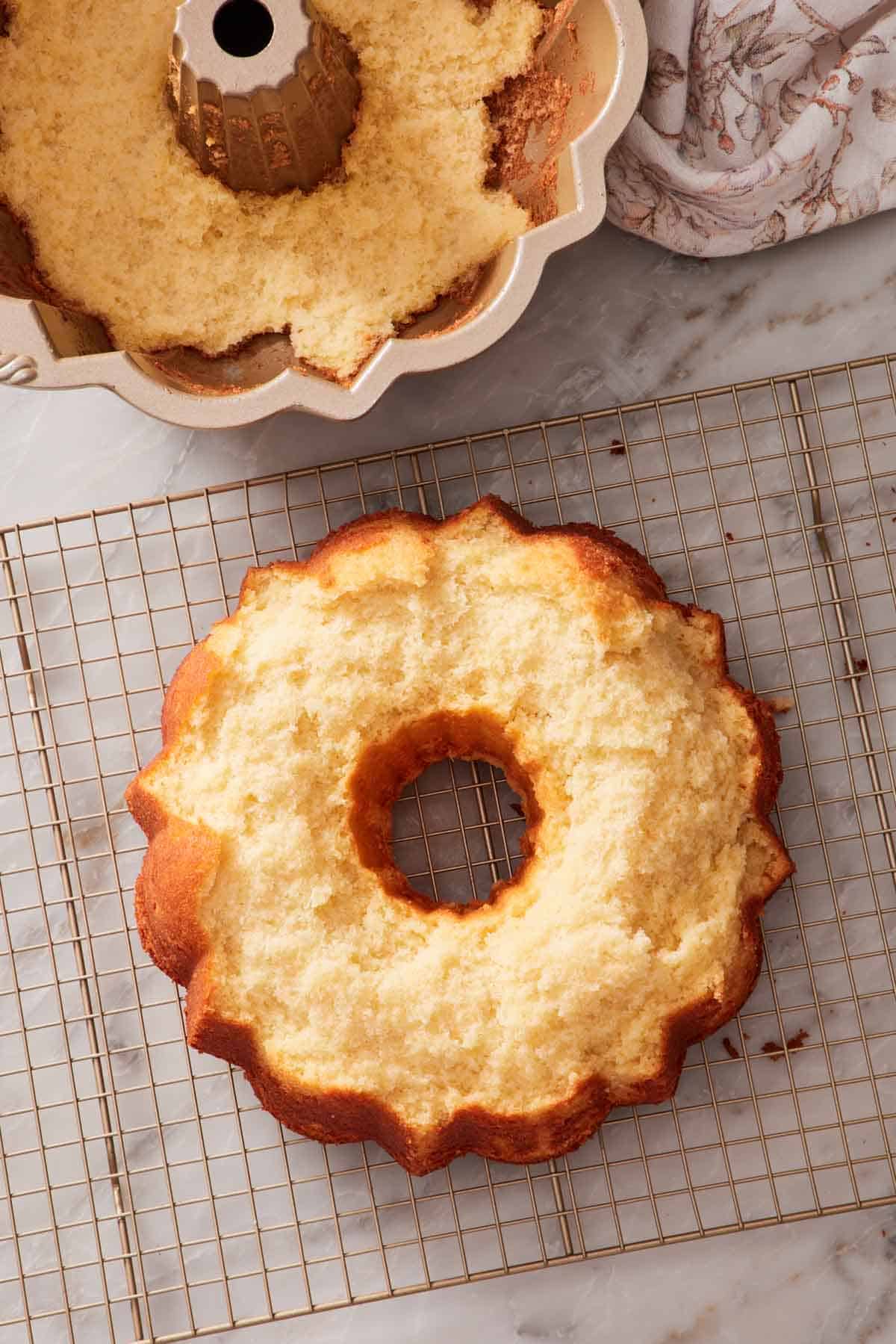 Overhead shot showing a Bundt cake on a wire rack. Some of the cake is still stuck to the pan, also in frame.