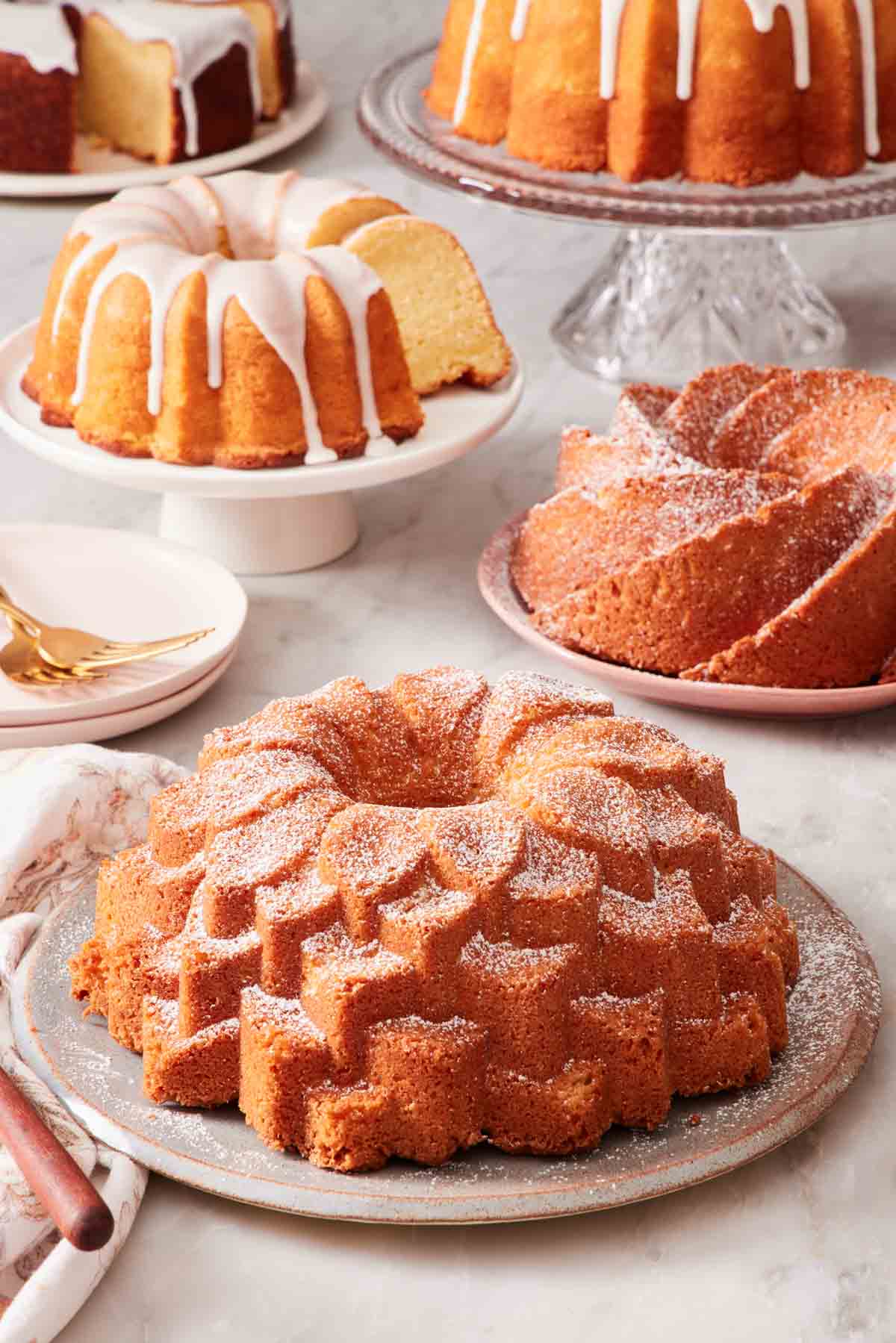 A Bundt cake dusted with powdered sugar, with other Bundt cakes in the background.