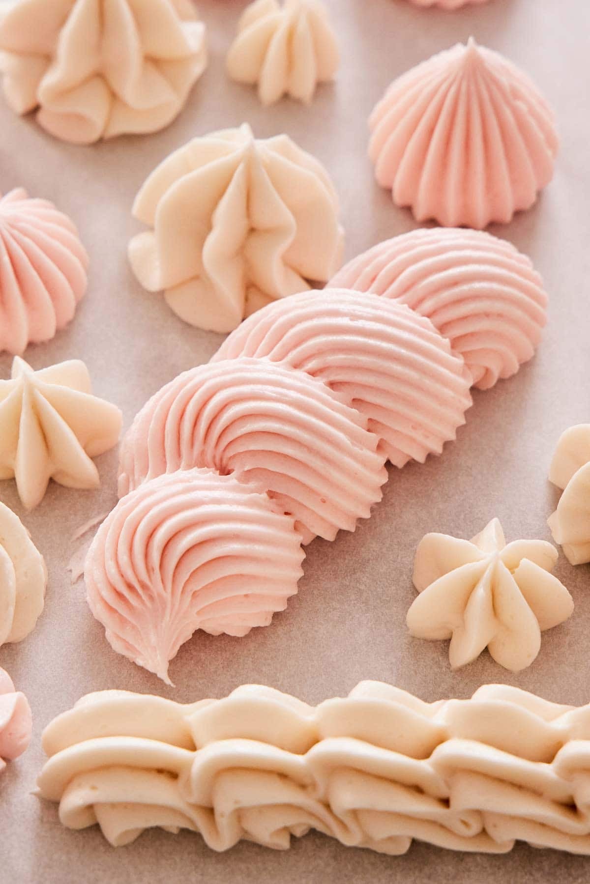 Buttercream frosting piped on parchment paper in different patterns and in different colors.