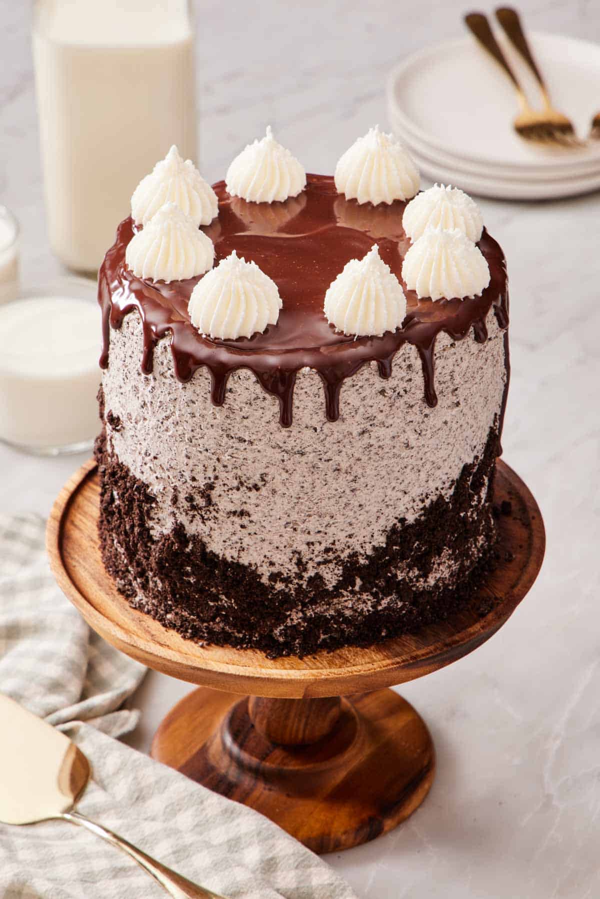 An Oreo cake on a wooden cake stand set on a marble countertop.