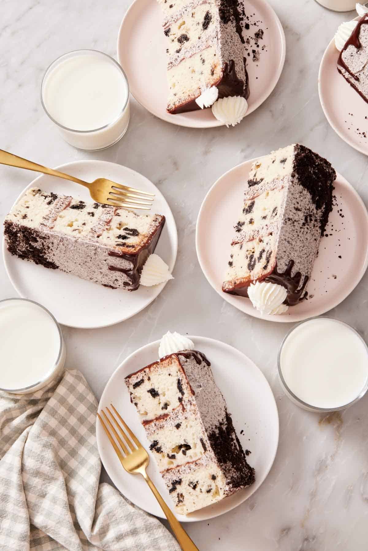 Overhead shot of slices of Oreo cake on small plates with glasses of milk.