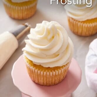 Pinterest graphic showing a close-up of a frosted cupcake on a small cake stand with more cupcakes out of focus in the background.