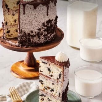 Pinterest graphic showing a slice of Oreo cake on a green plate with the rest of the cake on a cake stand behind it. Two glasses of milk and also a jug of milk off to the side.