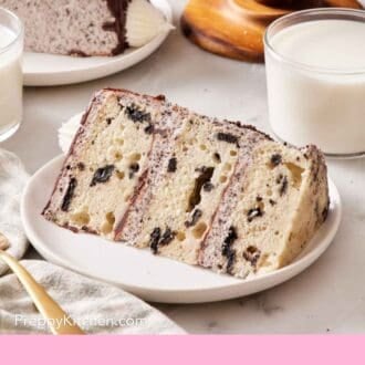 Pinterest graphic showing a slice of Oreo Cake on its side on a plate alongside a glass of milk. Another slice and glass surround it but mostly out of frame.