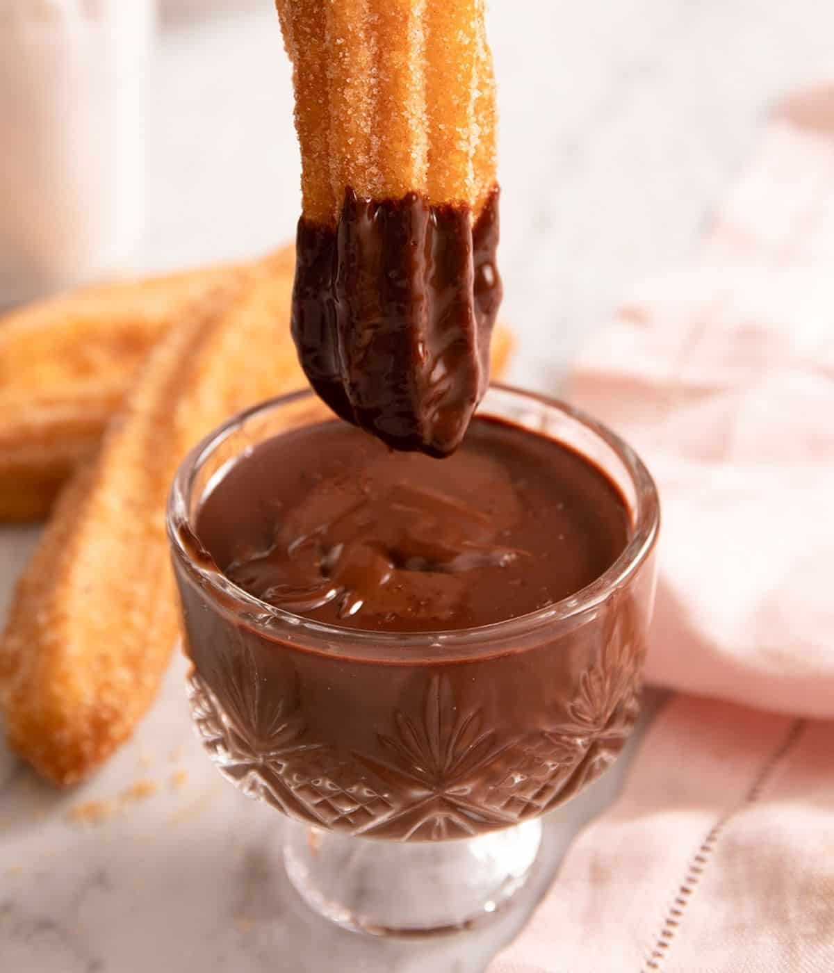 Close-up of a churro dipped into chocolate sauce.