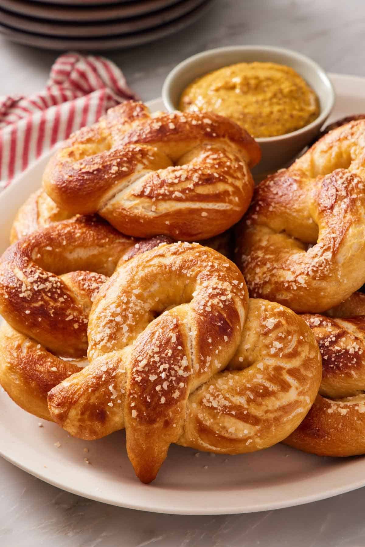 A pile of homemade soft pretzels with a dipping sauce.