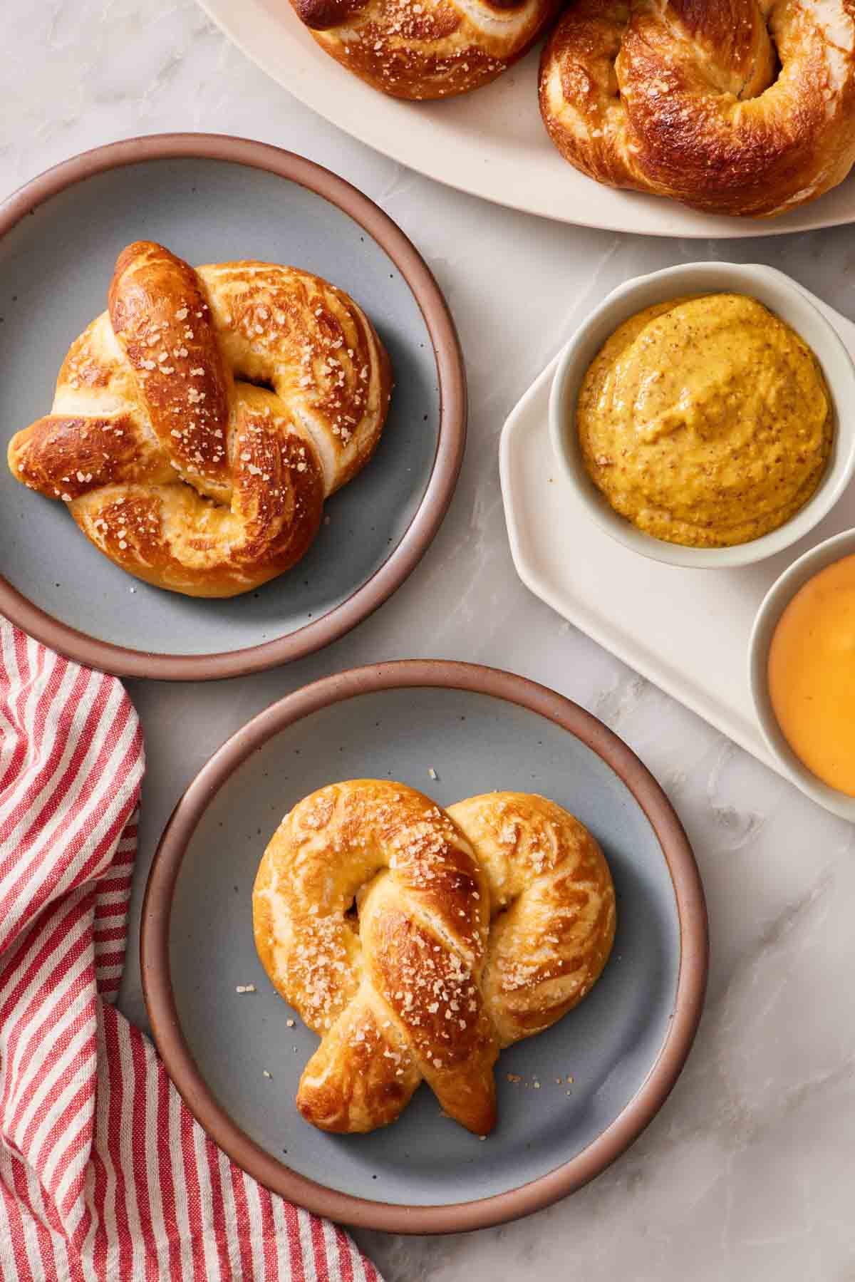 Overhead shot of soft pretzels on plates with sauces to the side.