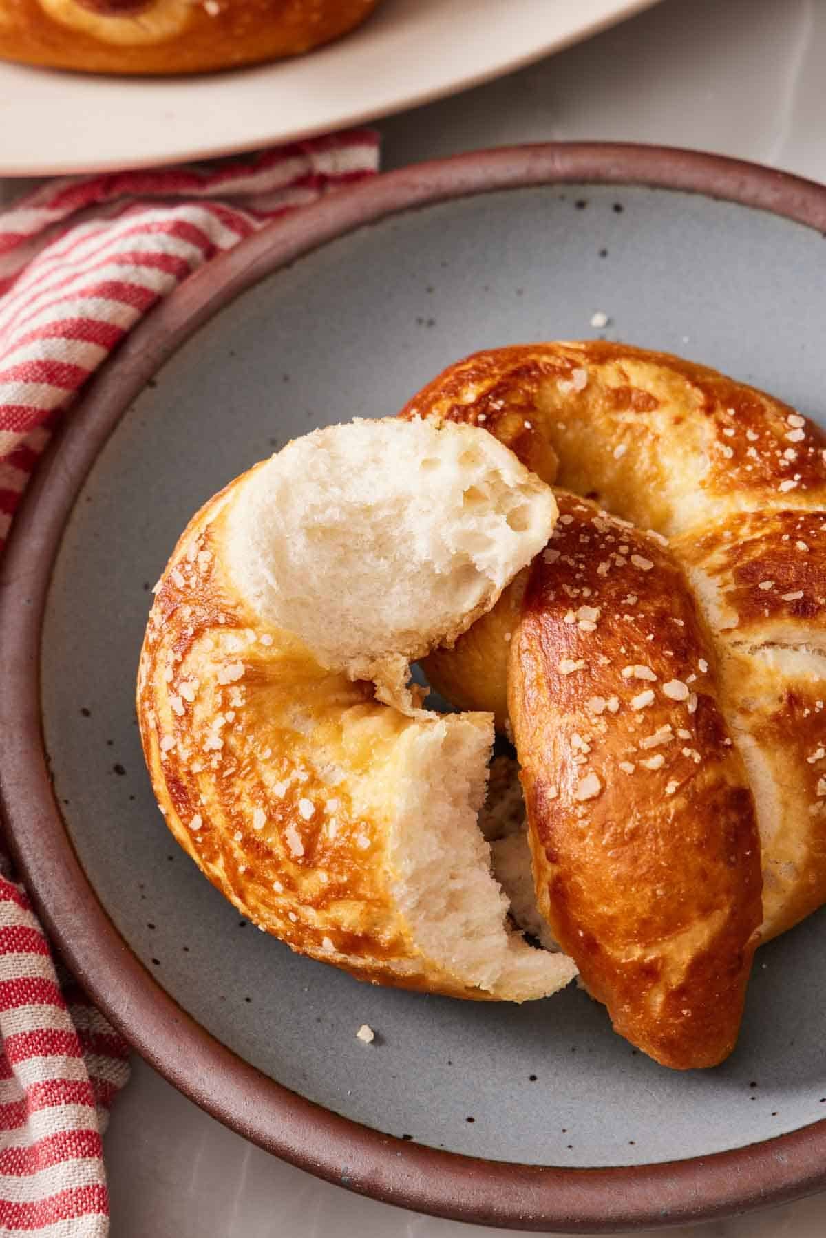 A torn soft pretzel on a plate to show off the soft interior.