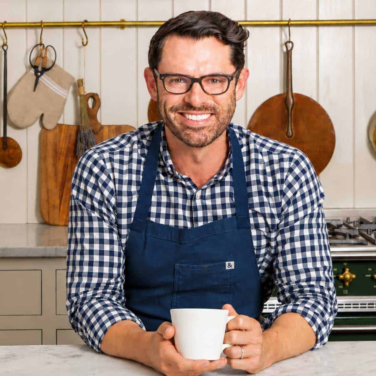 Photo of John Kanell holding a coffee cup in the kitchen.
