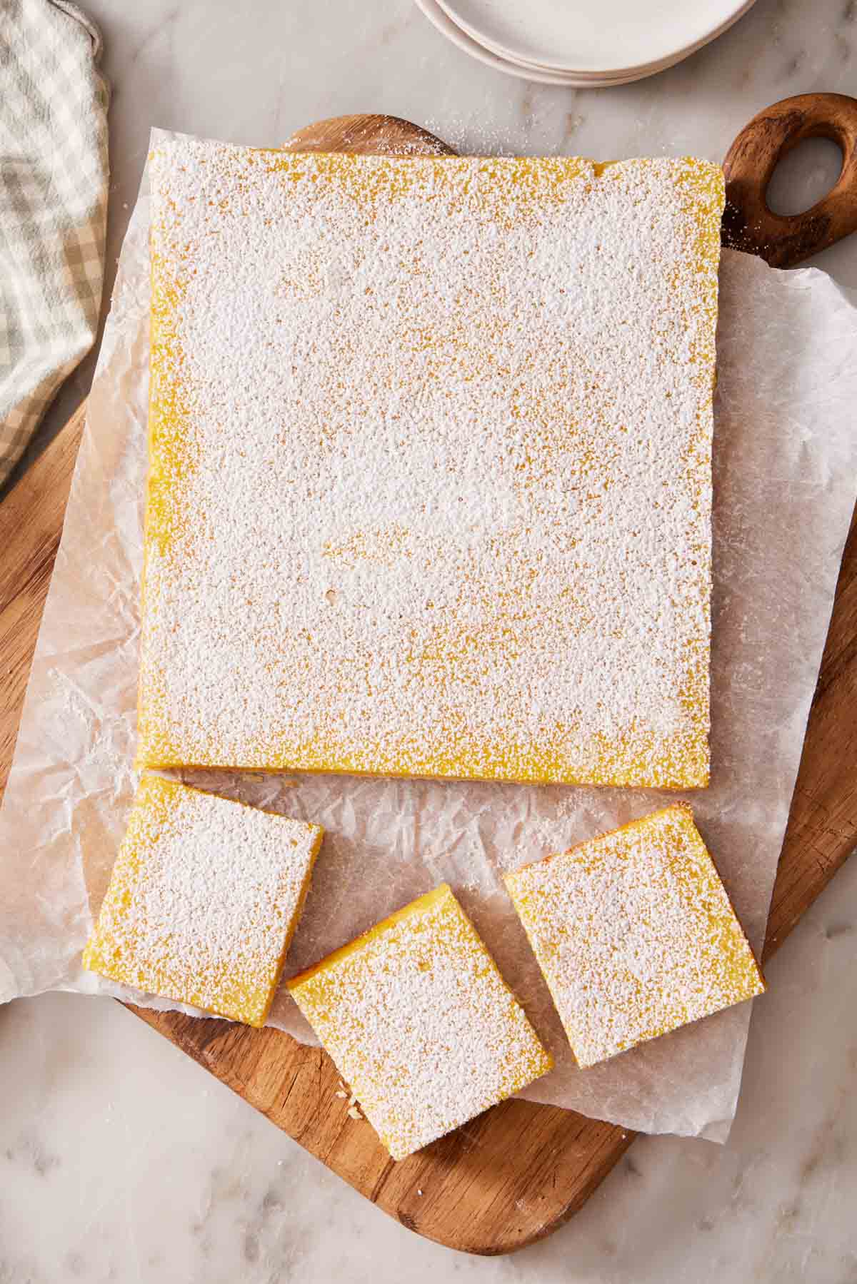 Overhead shot of a mostly unsliced lemon bar, with just a few pieces cut out.