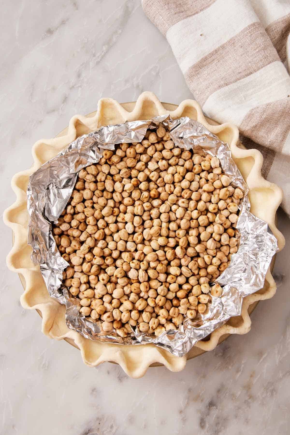 Overhead shot showing a pie crust filled with pie weights ready for blind baking.