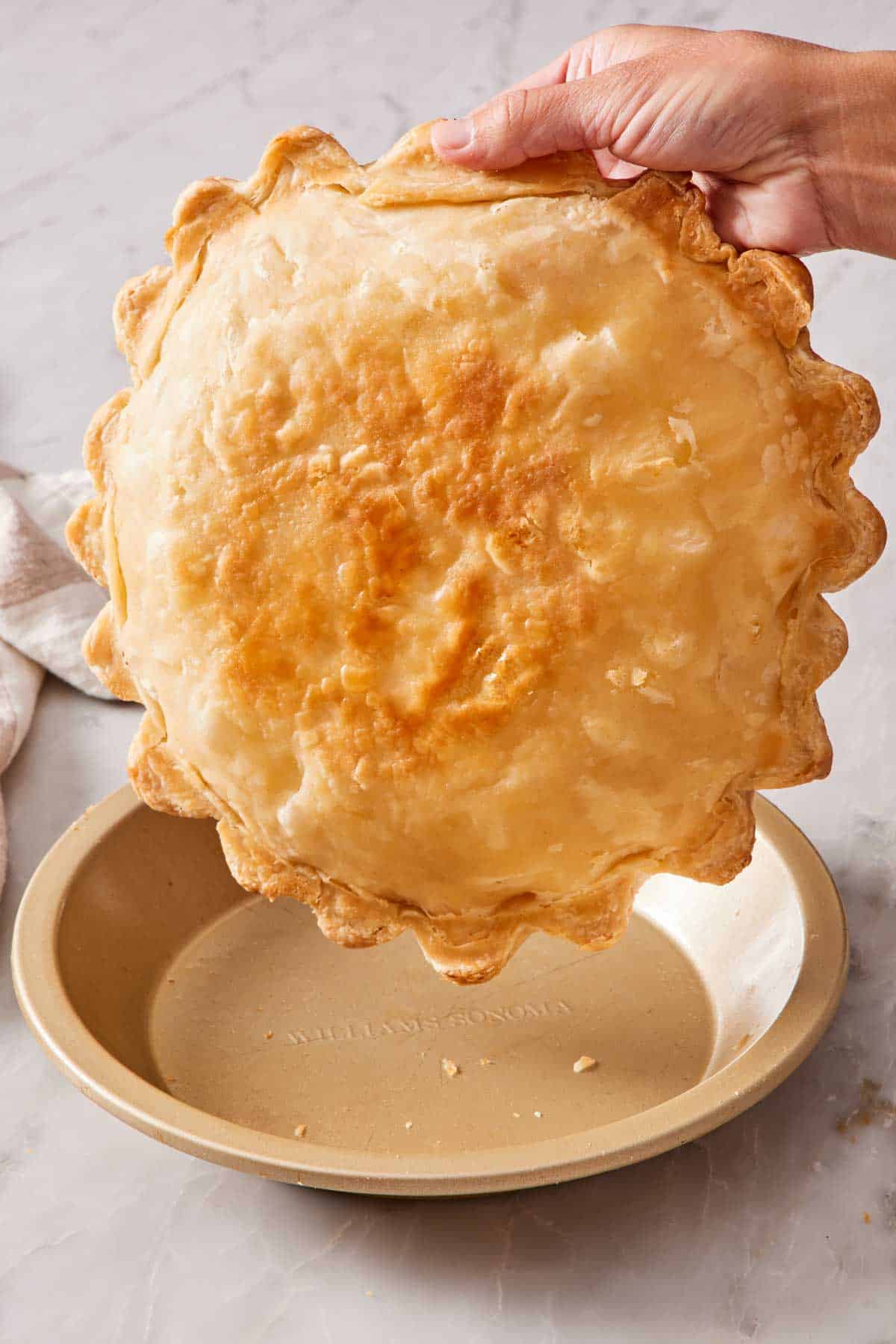 A baked pie crust lifted out of the pie dish to show the bottom.
