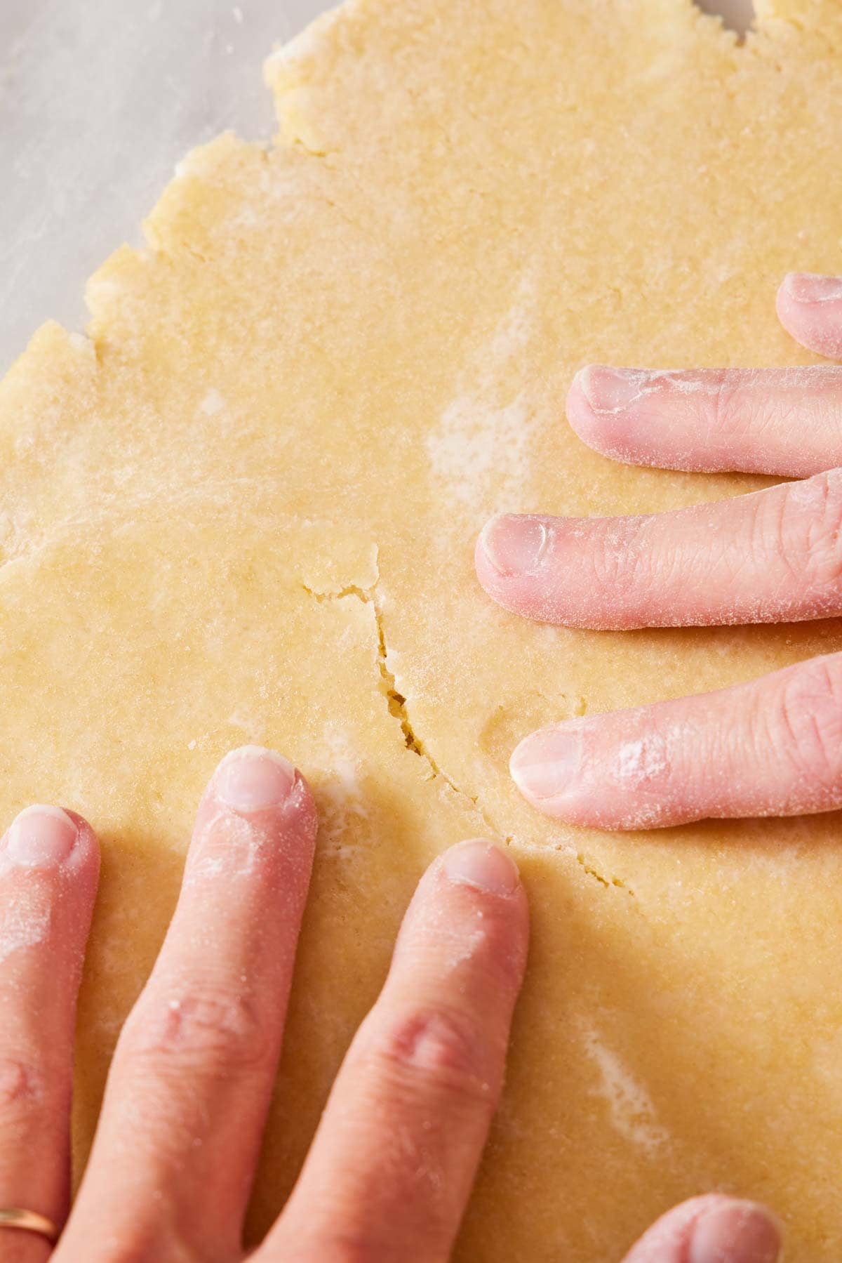 Close-up showing how to fix cracks in tart crust recipe dough.