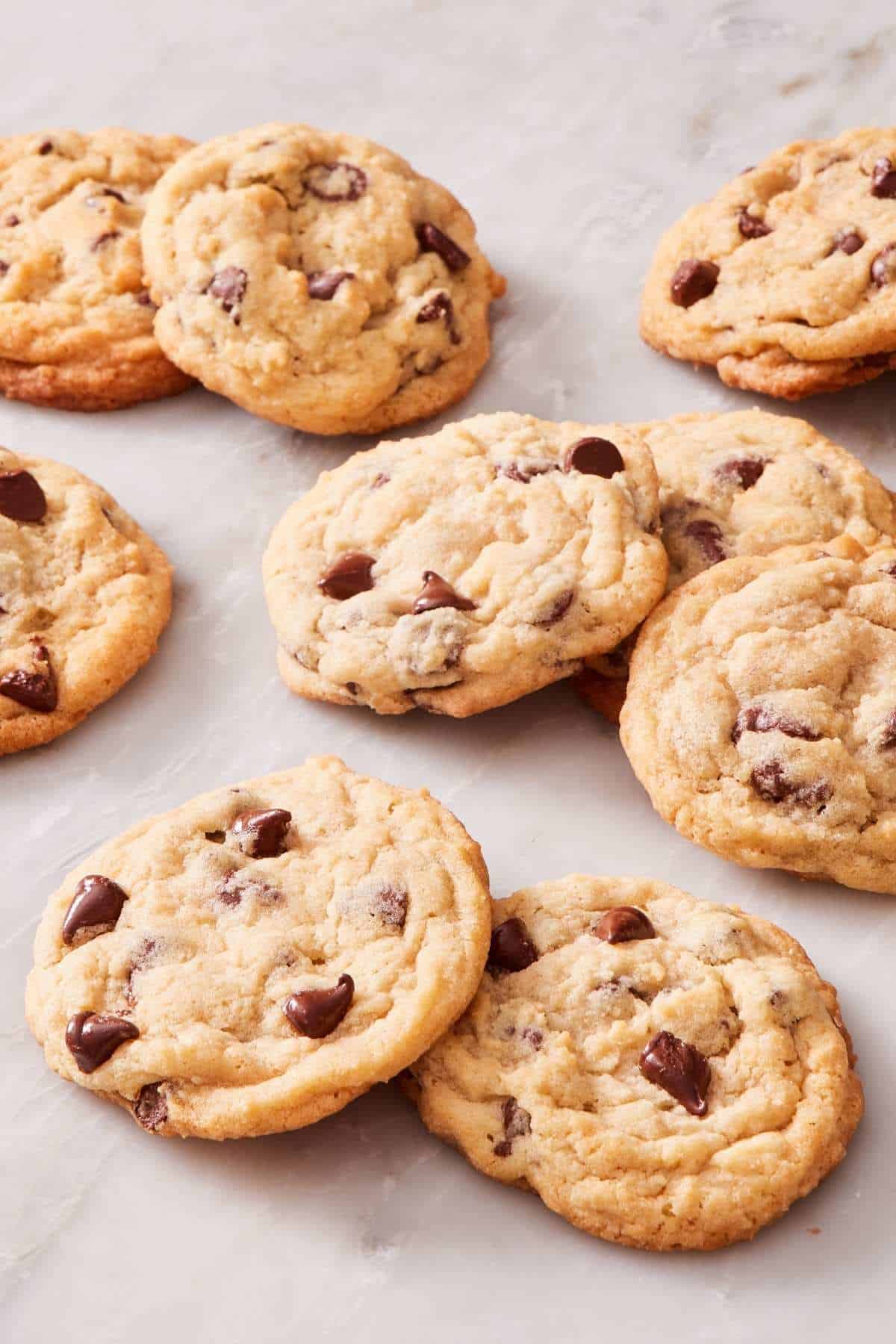 Lots of chocolate chip cookies on a marble countertop.
