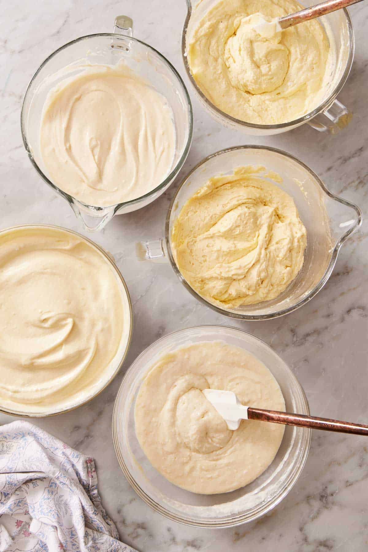 Overhead shot of several cake batters in containers that used different mixing methods.