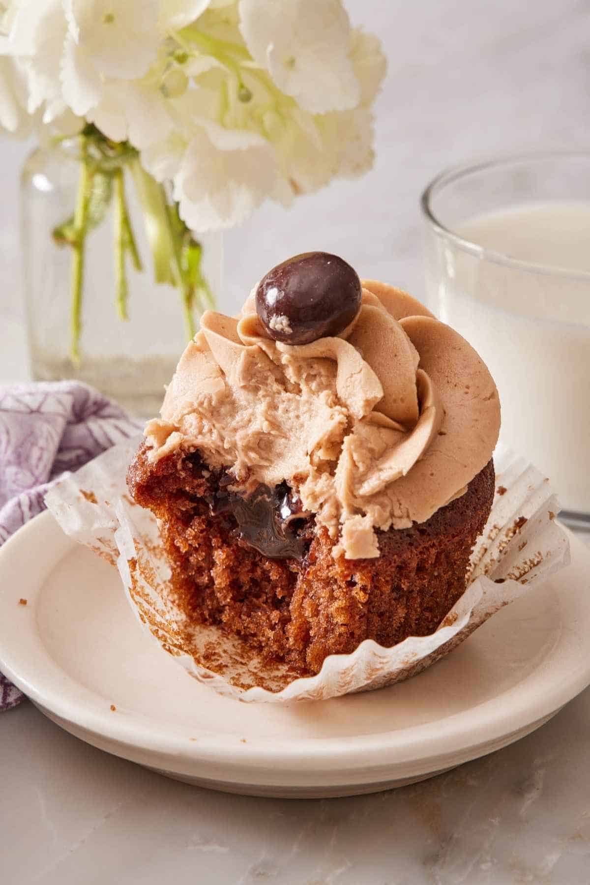 Close-up of a mocha cupcake on a small plate with a bite taken out.
