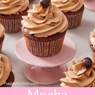 Pinterest graphic showing a mocha cupcake on a pink mini cake stand with more cupcakes on the counter around it.