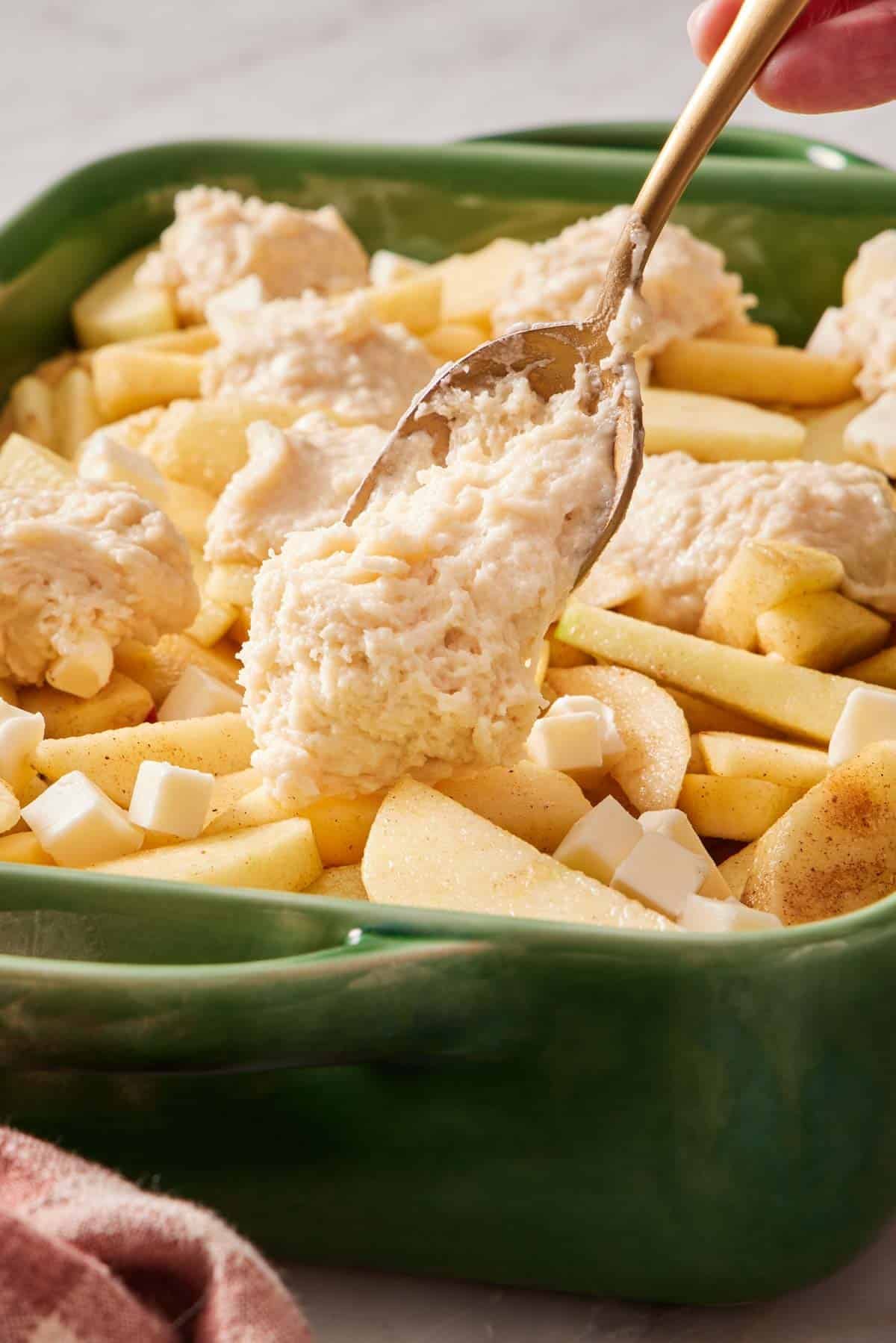 Cobbler batter spooned on top of apples.