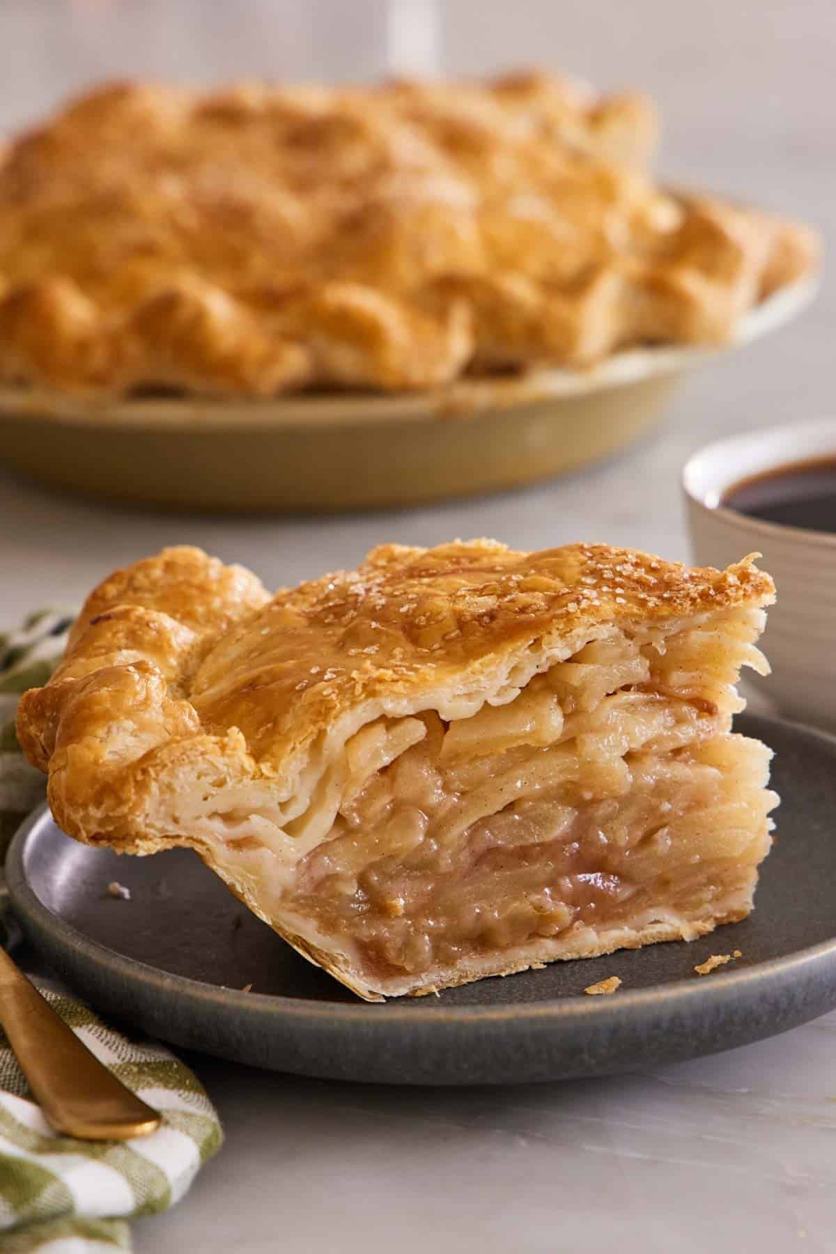 A slice of homemade apple pie on a dark plate.