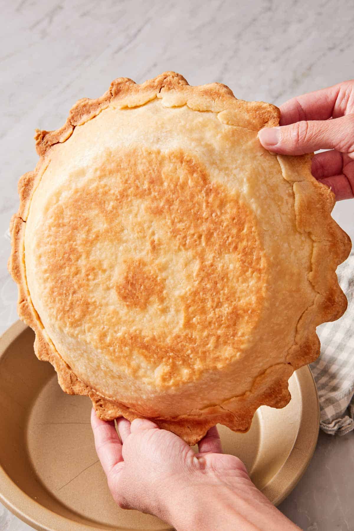 A blind-baked pie crust held up to show the bottom of the baked crust.